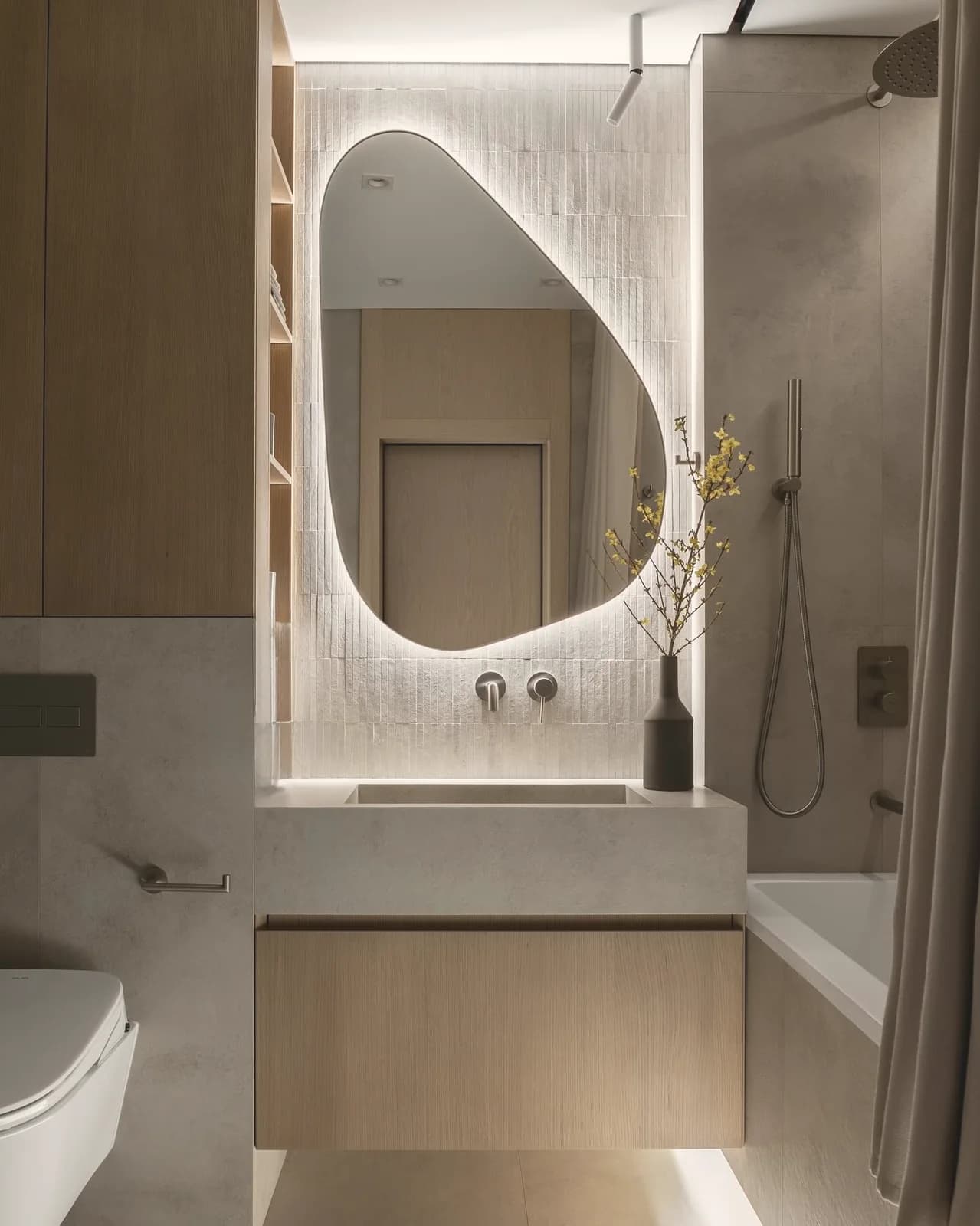 Stone bathroom with sculpted backlit mirror — London