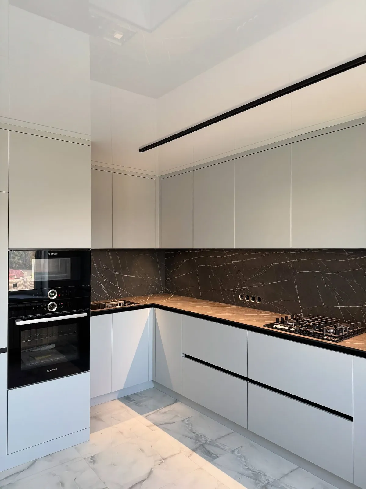Light grey kitchen with bronze marble splashback — Edmonton, London