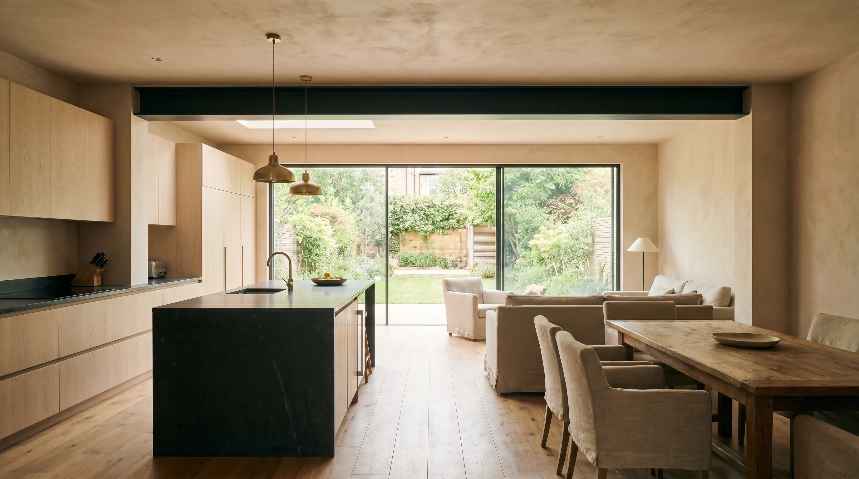 Open-plan London kitchen with an island, fitted units and a steel-beam knock-through opening into the rear reception room.