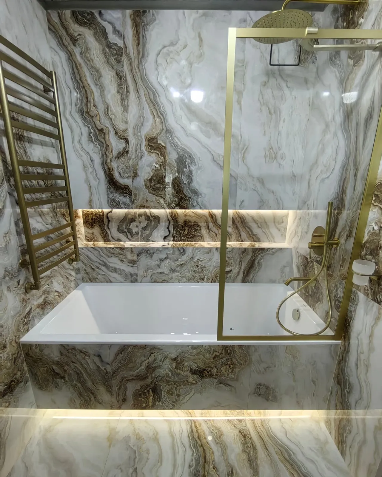 Book-matched onyx bathroom with brass fittings, completed by PrimeCraft Surface Solutions in Chigwell, Essex (IG7).