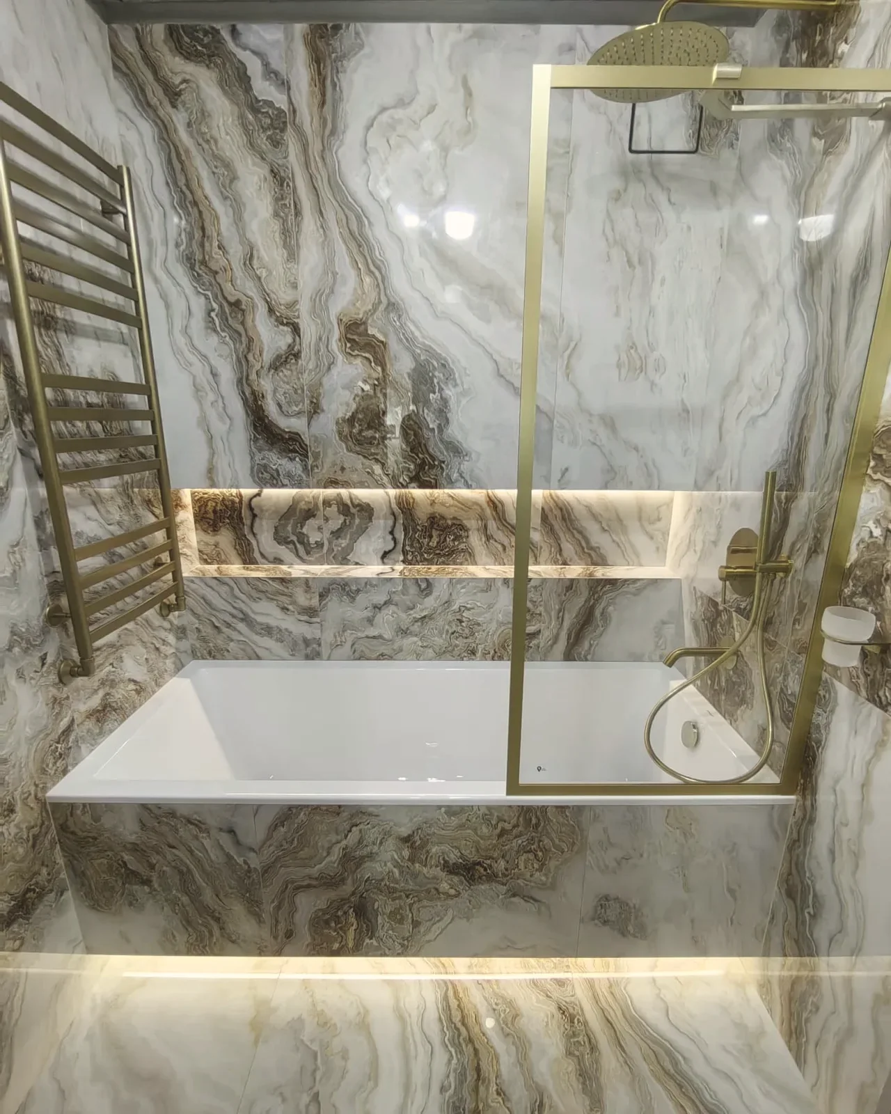Book-matched onyx bathroom with brass fittings, completed by PrimeCraft Surface Solutions in Chigwell, Essex (IG7).