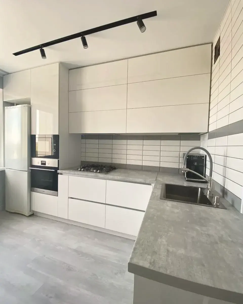 White gloss handleless kitchen with concrete-effect worktops, fitted by PrimeCraft Surface Solutions in Dartford, Kent (DA1).