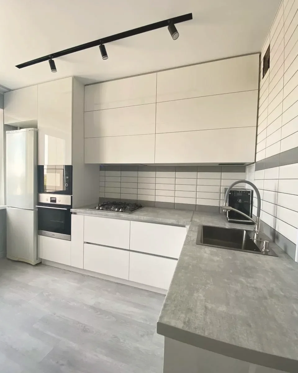 White gloss handleless kitchen with concrete-effect worktops, fitted by PrimeCraft Surface Solutions in Dartford, Kent (DA1).